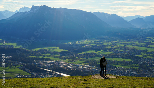 Couple kiss at the top Untersberg mountain and background with aerial panorama of Salzburg in Austria.