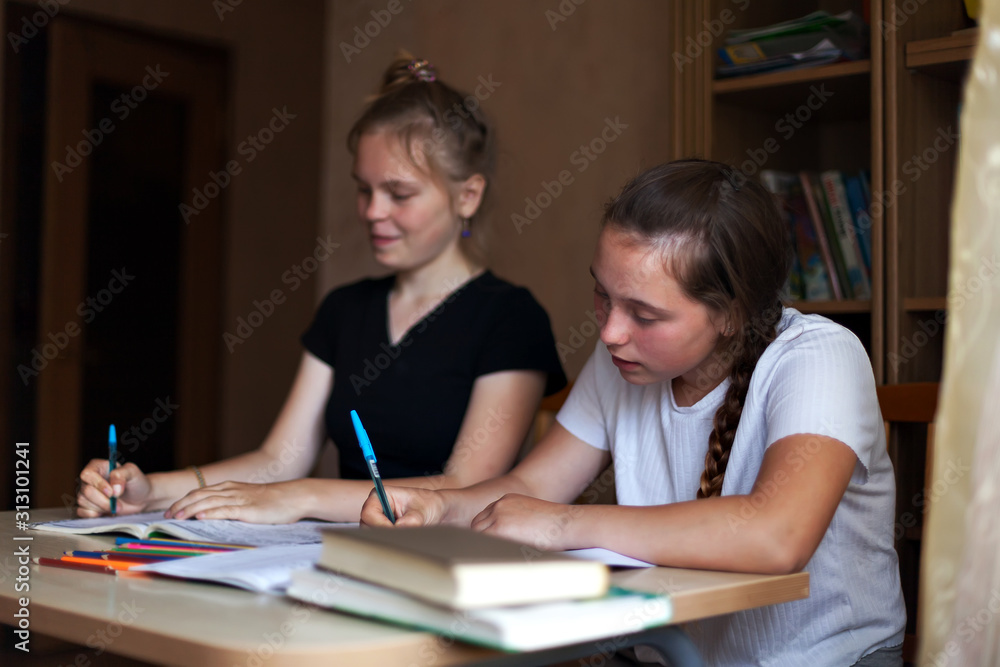 Two girls doing homework at table Two girls doing homework at table
