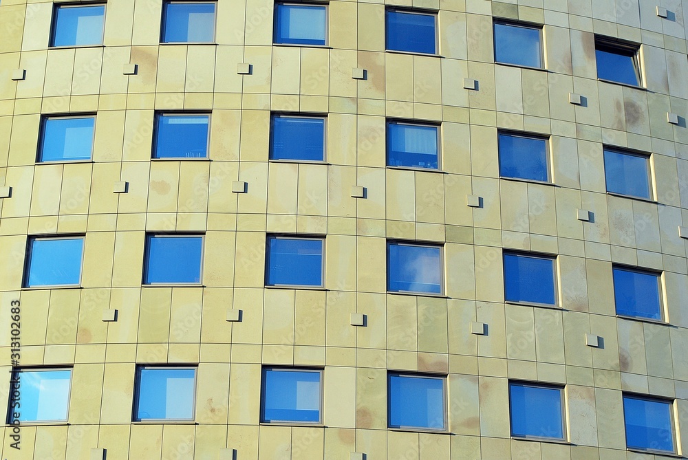Modern office building wall made of steel and glass with blue sky