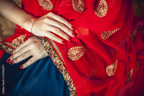 hands with red manicure on a red-blue sari
