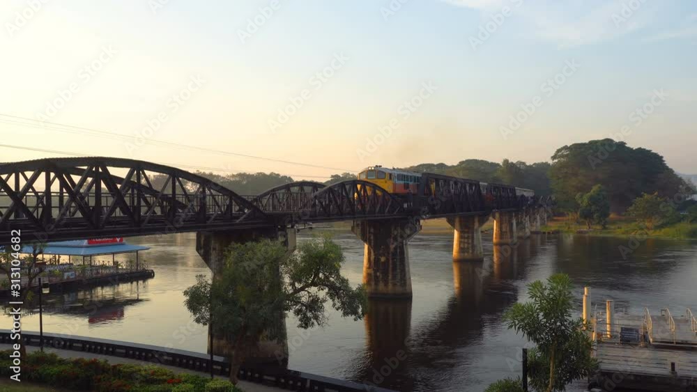 Bridge over the River Kwai in morning time with tourists and monks walking on the bridge. Is an important landmark and a tourist destination Bridge over the River Kwai in morning time with tourists and monks walking on the bridge. Is an important landmark and a tourist destination