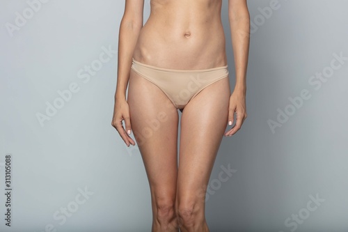  Woman in beige panties on a gray background