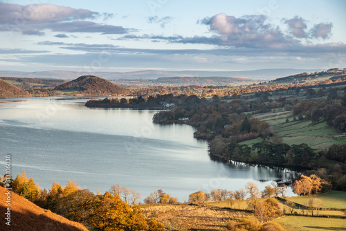 Fototapeta Naklejka Na Ścianę i Meble -  Beautiful Autumn Fall landscape of Ullswater and surrounding mountains and hills viewed from Hallin Fell on a crisp cold morning with majestic sunlgiht on the hillsides