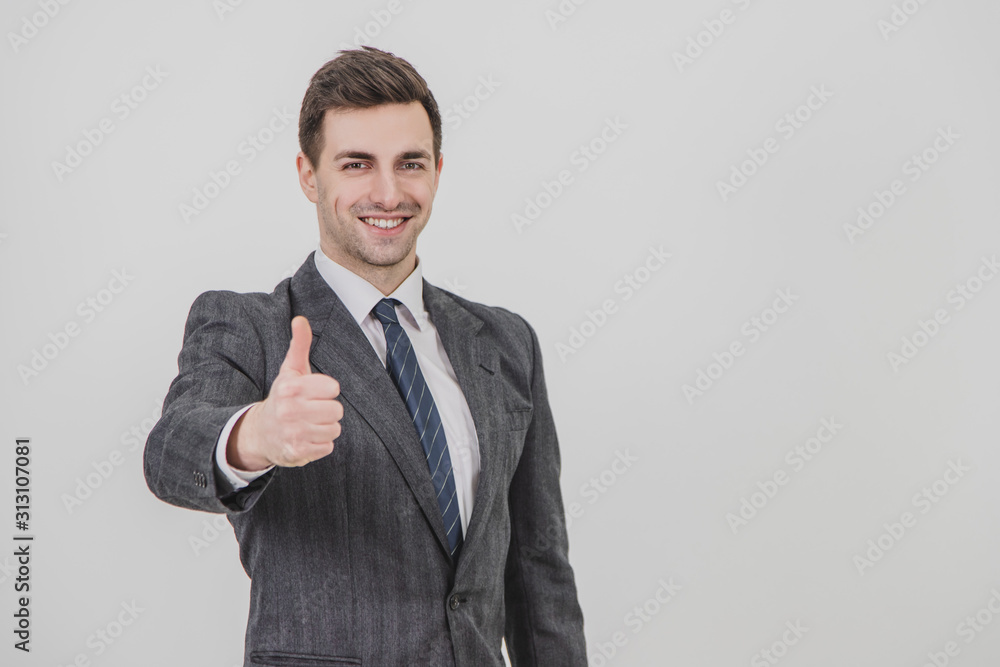 Handsome businessman standing, giving thumb up, smiling, showing his satisfaction. Handsome businessman standing, giving thumb up, smiling, showing his satisfaction.