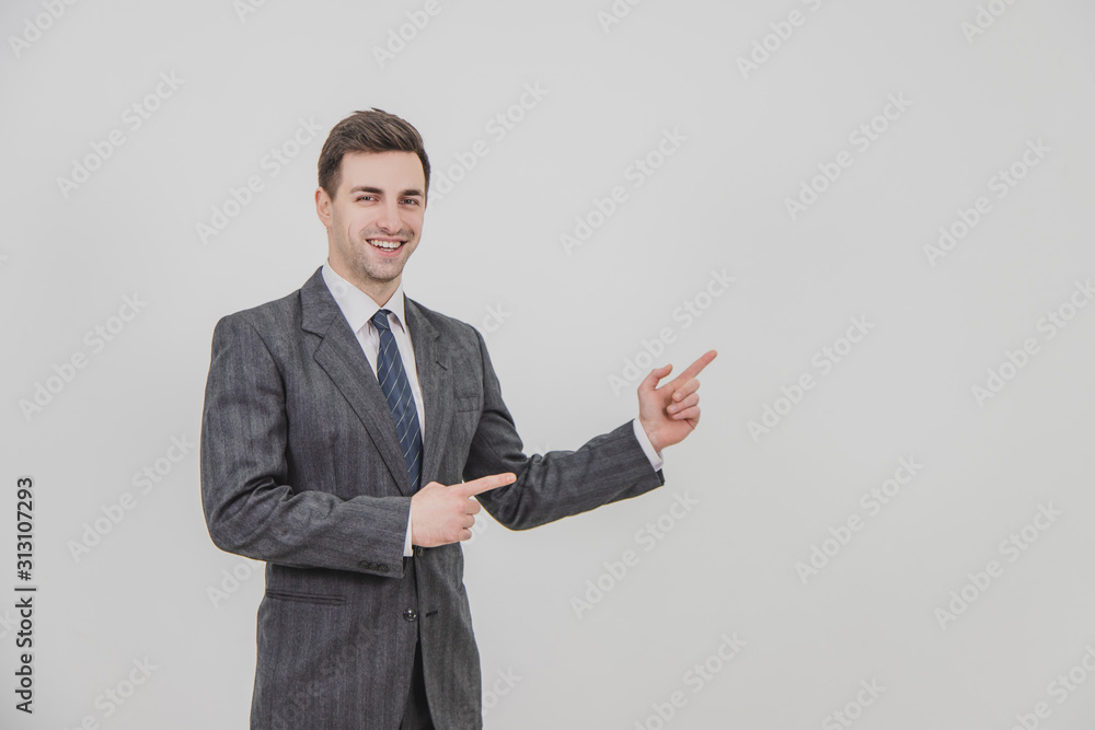 Successful handsome businessman standing, presenting a project, pointing his fingers at the copyspace for text or product. Successful handsome businessman standing, presenting a project, pointing his fingers at the copyspace for text or product.