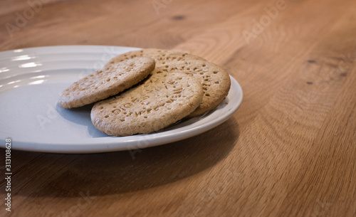 Digestive sweetmeal biscuits on white plate placed on wooden table. photo