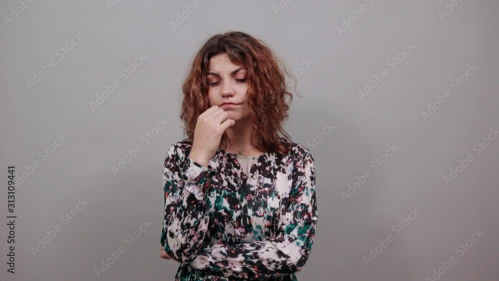 Unhappy charming young lady over isolated gray background in fashion shirt biting nails on mouth, looking angry, having nice ring. People emotions. Lifestyle concept Unhappy charming young lady over isolated gray background in fashion shirt biting nails on mouth, looking angry, having nice ring. People emotions. Lifestyle concept