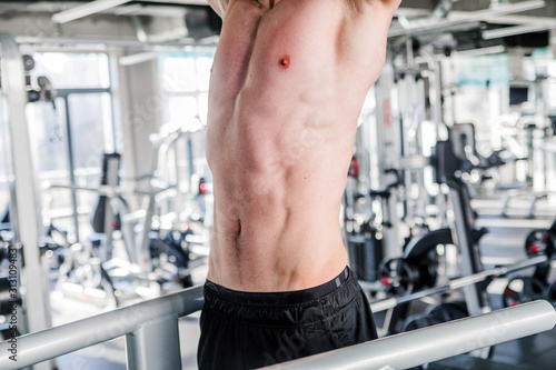 A man with a naked torso is engaged in the gym. Beautiful pumped up press closeup