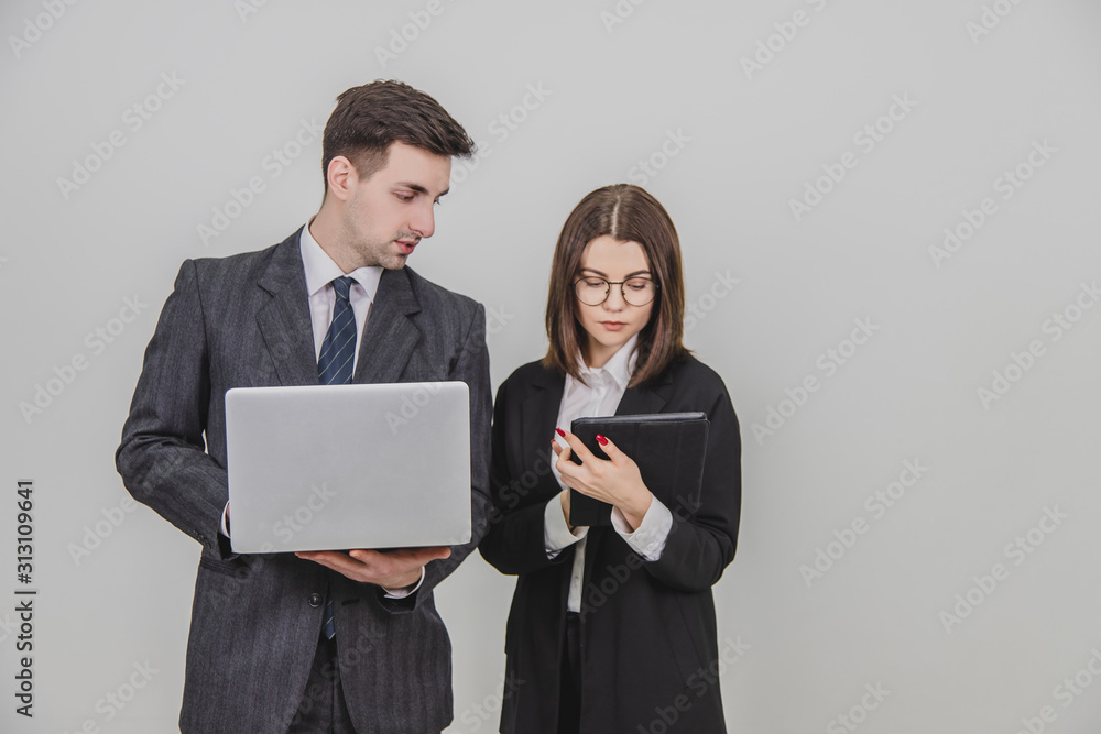 Young business couple standing, using digital tablet and laptop together. Young business couple standing, using digital tablet and laptop together.
