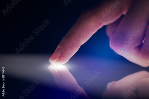 Finger touching tablet with dark background with copyspace photo