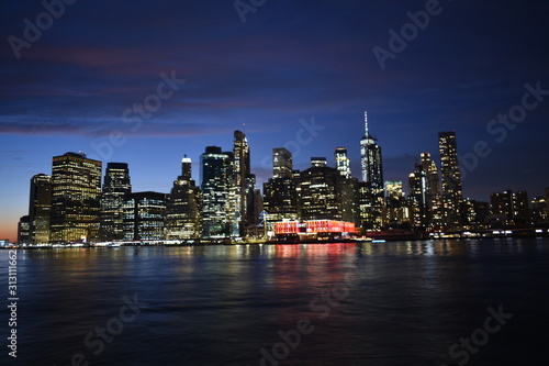 New york skyline from brooklyn at night with water reflection