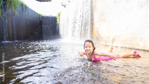 Fototapeta Naklejka Na Ścianę i Meble -  happy little asian girl playing water in spillway of weir