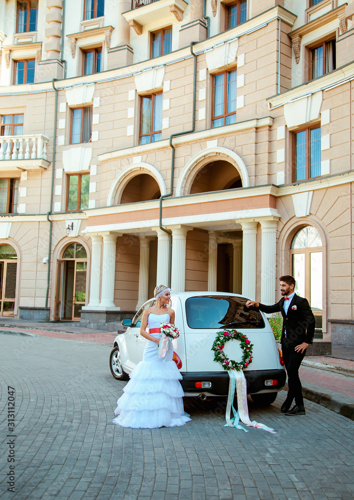 Obraz premium beautiful, loving couple on a wedding walk with a car