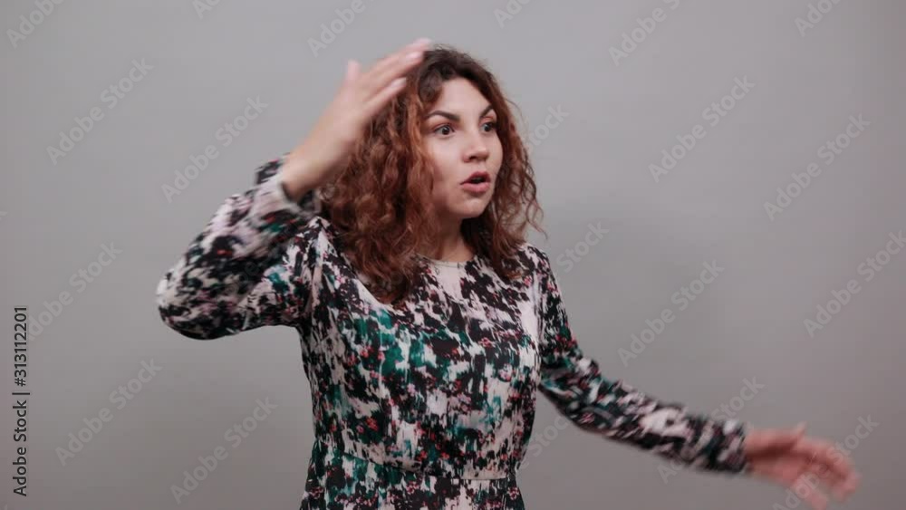 Surprised charming young lady spreads hands, looking into distance, hugging herself over isolated gray background in fashion shirt. Lifestyle concept Surprised charming young lady spreads hands, looking into distance, hugging herself over isolated gray background in fashion shirt. Lifestyle concept