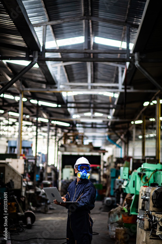 Officials from the Department of Hazardous substances control bureau is investigating the leak of a hazardous chemical in a chemical plant. Man with protective mask and computer laptops in factory