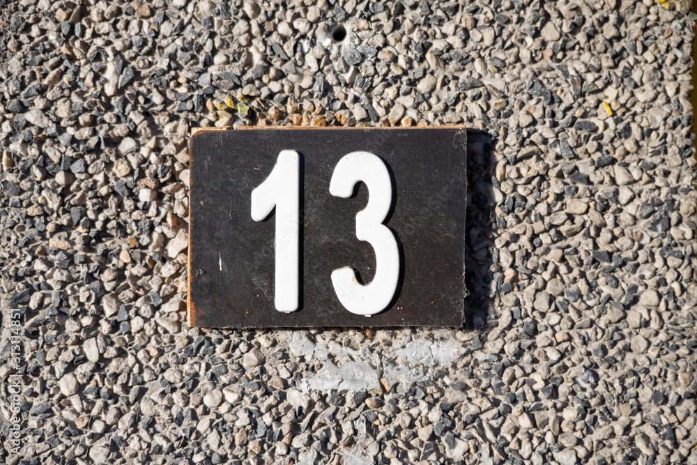 Number 13, thirteen, street number sign on the wall Number 13, thirteen, street number sign on the wall