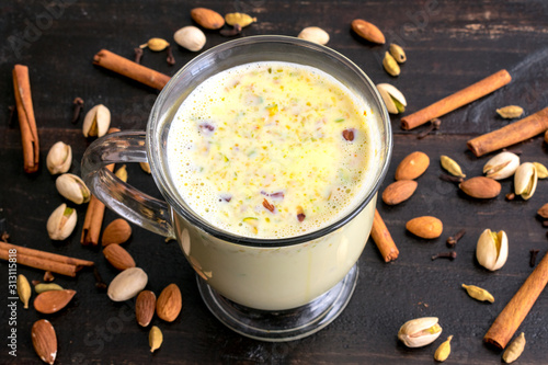 Mug of Masala Paal Surrounded by Nuts and Spices photo