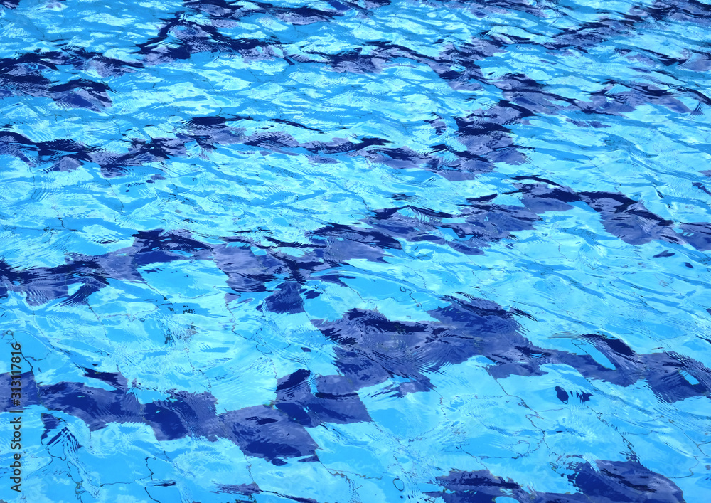 The water surface of the swimming pool turquoise color, illuminated by the sun