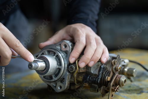 Mechanic man trying to remove seal shaft of diesel injection pump, mechanical maintenance and repair background