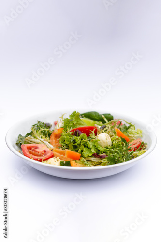 white deep plates with fresh salad ingredients mixed with sauce placed on isolated white background. A place for a menu, banner or advertisement