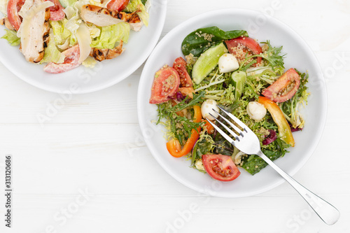 white deep plates with fresh salad ingredients mixed with sauce placed on an attractive background. A place for a menu, banner or advertisement
