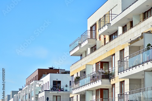 Contemporary residential building exterior in the daylight. Modern apartment buildings on a sunny day with a blue sky. Facade of a modern apartment building © Grand Warszawski