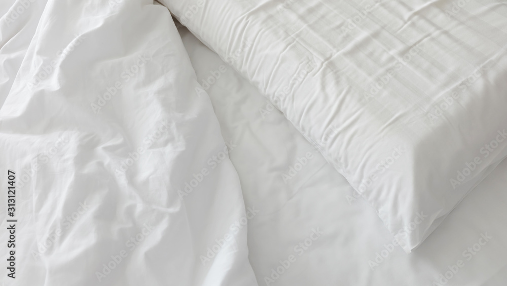 White linen, duvet, and pillow with creases.