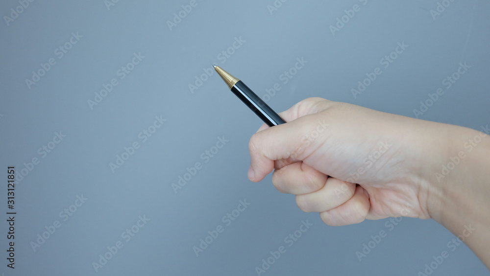 Hand gripping on a ball pen and pointing it at an angle, with copy space on the left. Hand gripping on a ball pen and pointing it at an angle, with copy space on the left.