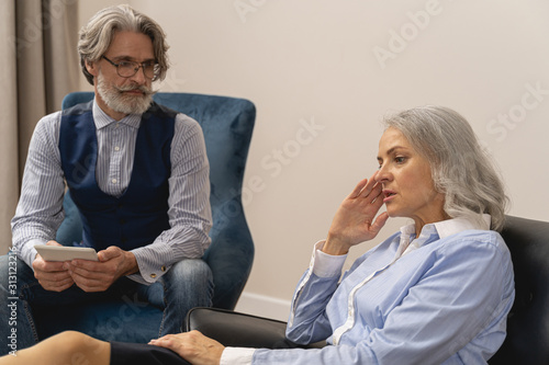 Psychoanalyst sitting next to his female patient