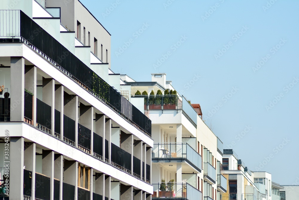 Obraz premium Contemporary residential building exterior in the daylight. Modern apartment buildings on a sunny day with a blue sky. Facade of a modern apartment building