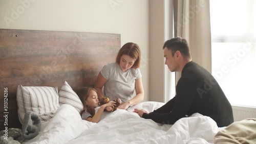 Lovely careful family take care of sick daughter on bed, caucasian family at home treating ill kid girl