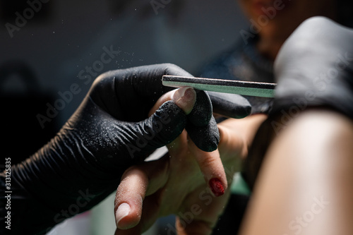 woman in a nail salon receiving a manicure by a beautician photo