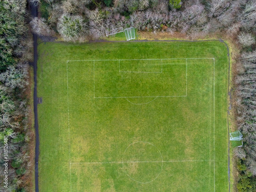 Aerial view on a football field surrounded by trees in a park.