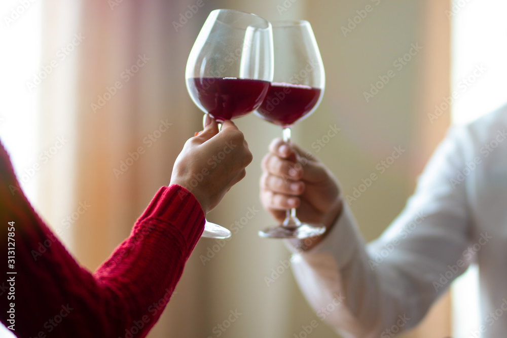A cheerful young couple crossing their wineglasses at a restaurant. A man and his girlfriend drinking wine at a cafe. Red rose on a table. Valentine's day concept. A cheerful young couple crossing their wineglasses at a restaurant. A man and his girlfriend drinking wine at a cafe. Red rose on a table. Valentine's day concept.
