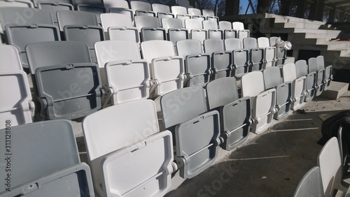 Many rows of white - grey plastic seats in the stadium