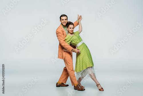 stylish dancers looking at camera while dancing boogie-woogie on grey background photo