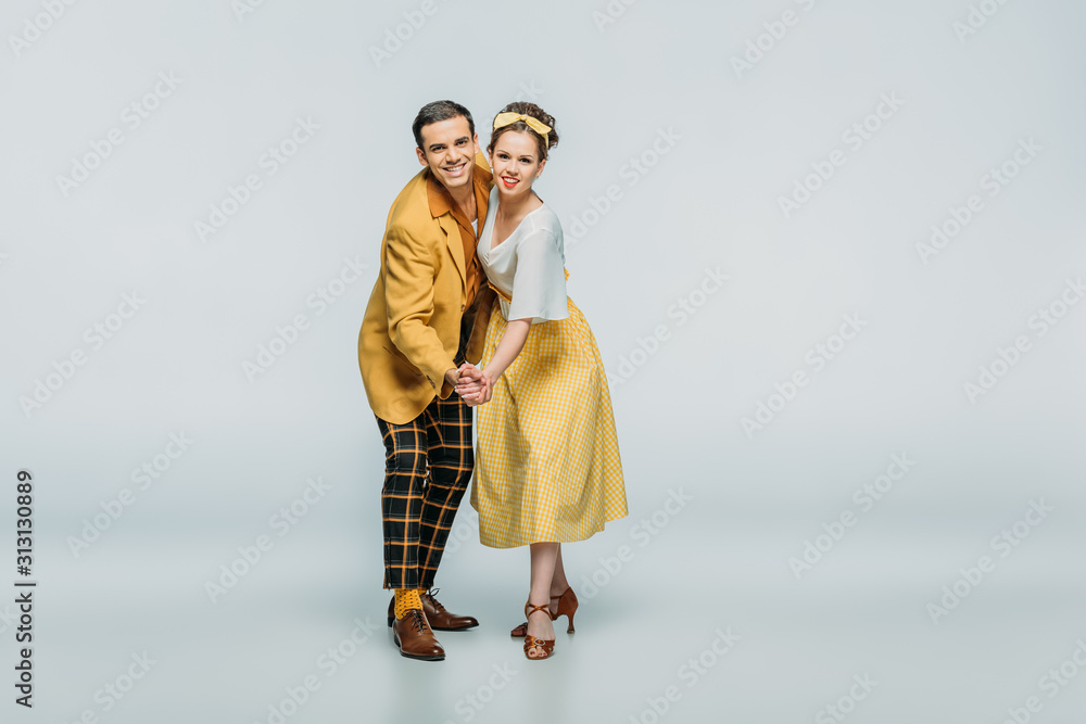 Φωτογραφία stylish dancers holding hands while dancing boogie-woogie on grey background