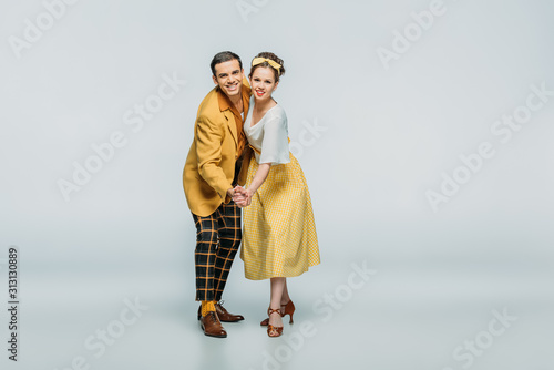 Fotografi stylish dancers holding hands while dancing boogie-woogie on grey background