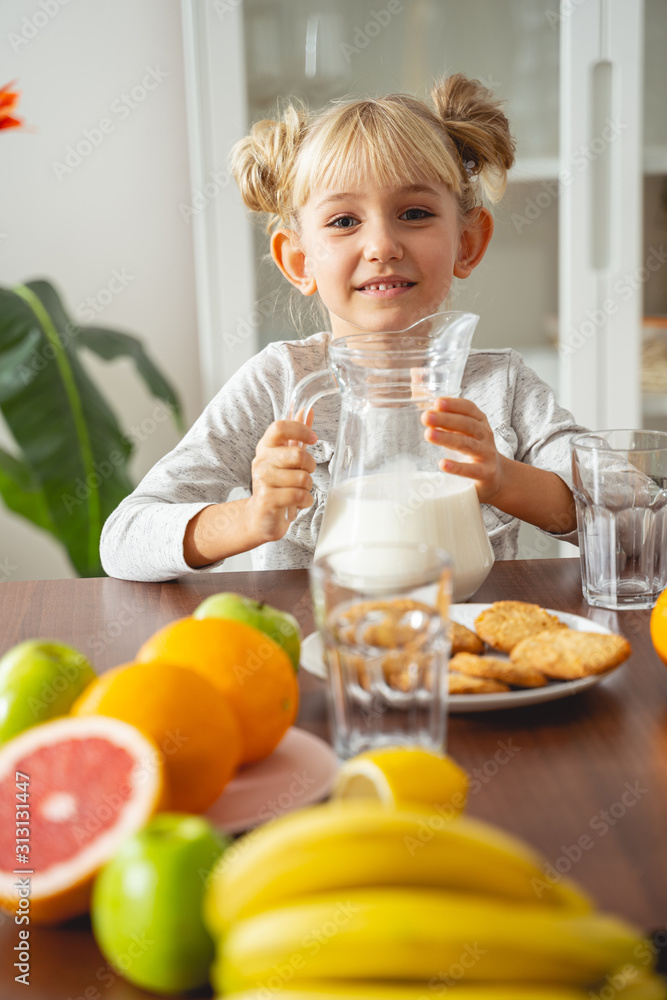 Joyful little girl sitting at the kitchen table at home Joyful little girl sitting at the kitchen table at home
