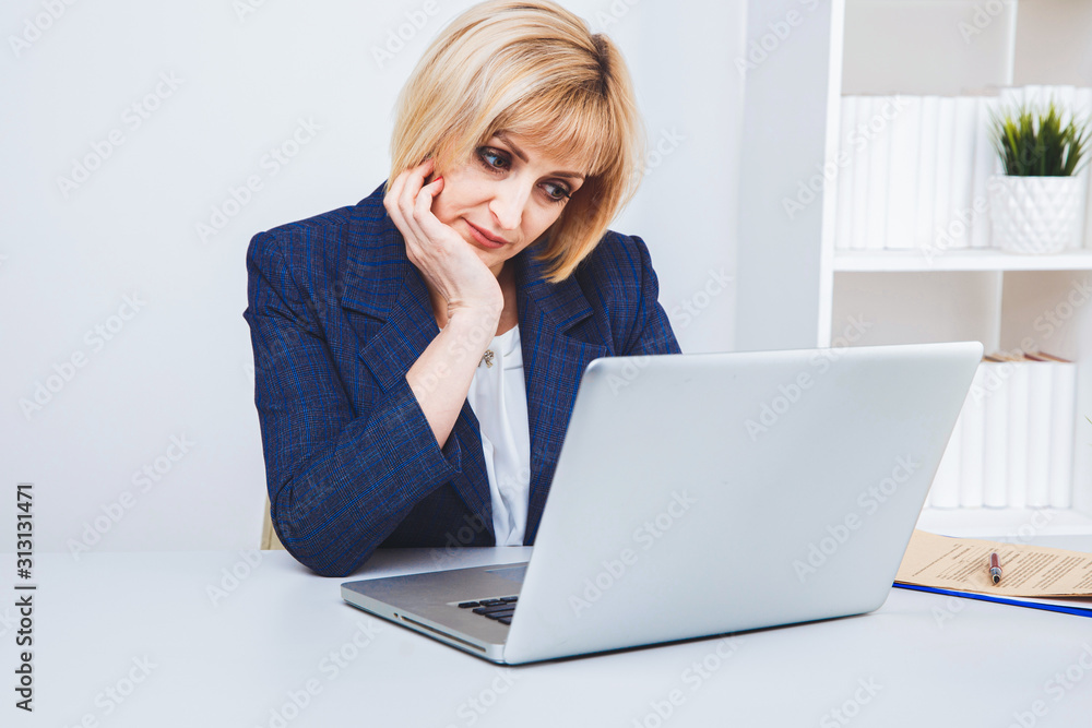 Blond woman sitting at the desk in office and working Blond woman sitting at the desk in office and working