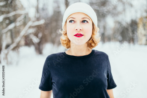 Beautiful winter look with snowfall - fashionable glamorous young attractive blonde in a black t-shirt outside in the cold - fashion photo