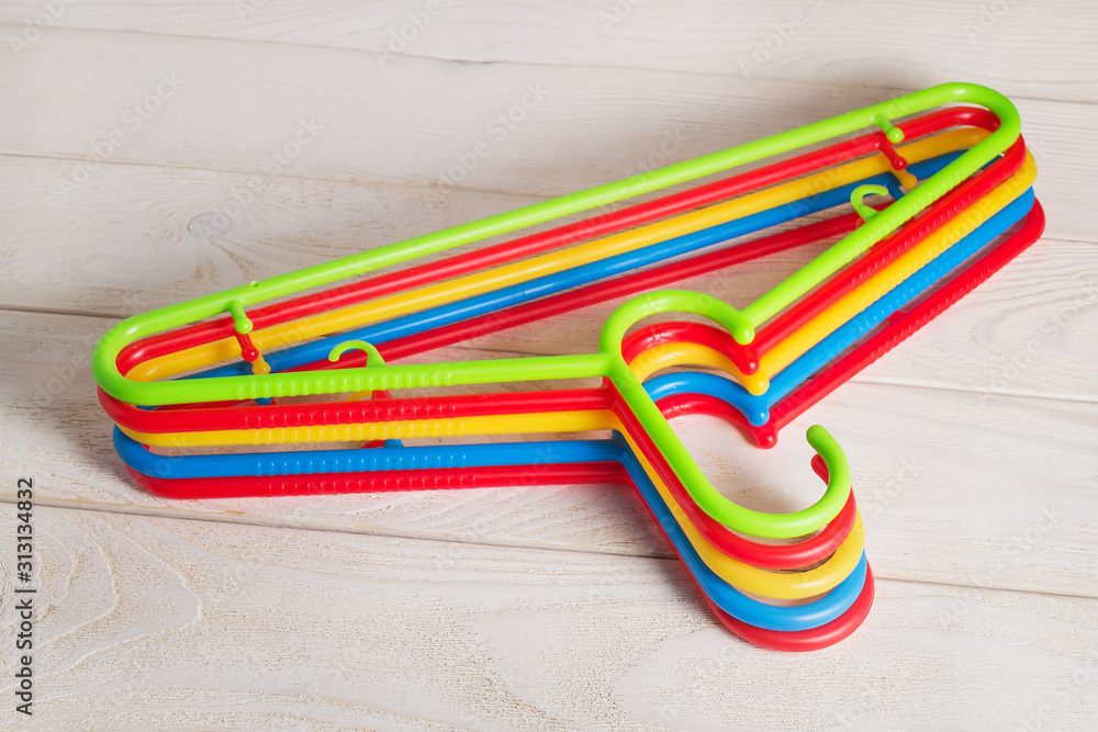 Five multicolored plastic clothes hangers on a light wooden surface. Set of new colorful plastic clothes hangers. Household items. Domestic life. Five multicolored plastic clothes hangers on a light wooden surface. Set of new colorful plastic clothes hangers. Household items. Domestic life.