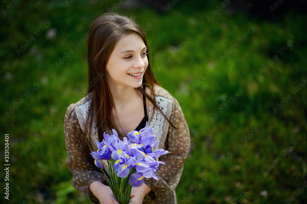 Beautiful girl rejoices and smiles with a bouquet of spring flowers in her hands. Soft focus. Beautiful girl rejoices and smiles with a bouquet of spring flowers in her hands. Soft focus.
