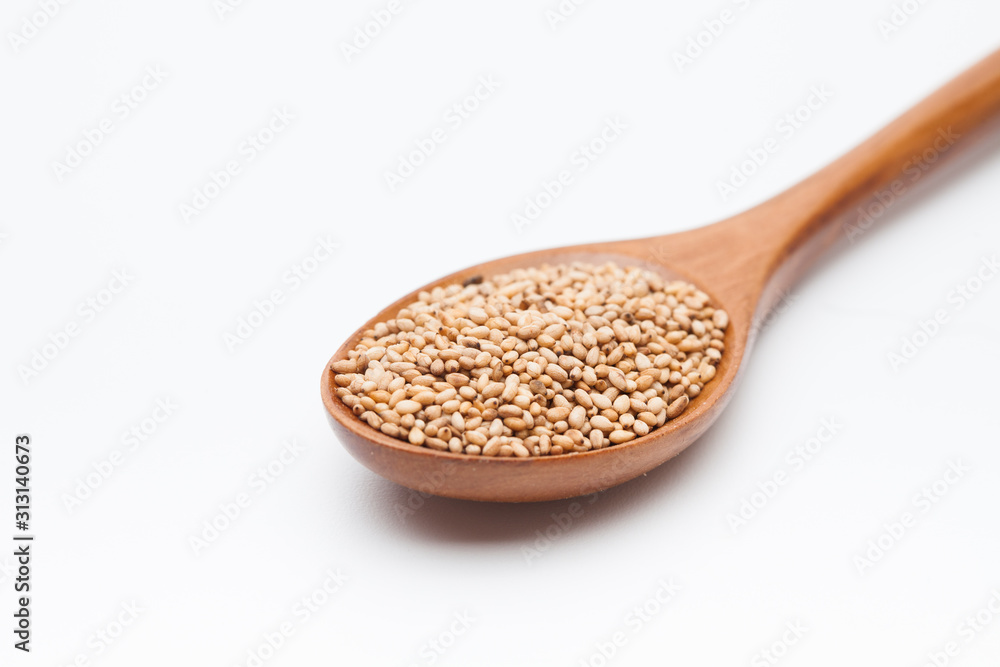 Toasted Sesame seeds in wooden spoon on white Toasted Sesame seeds in wooden spoon on white