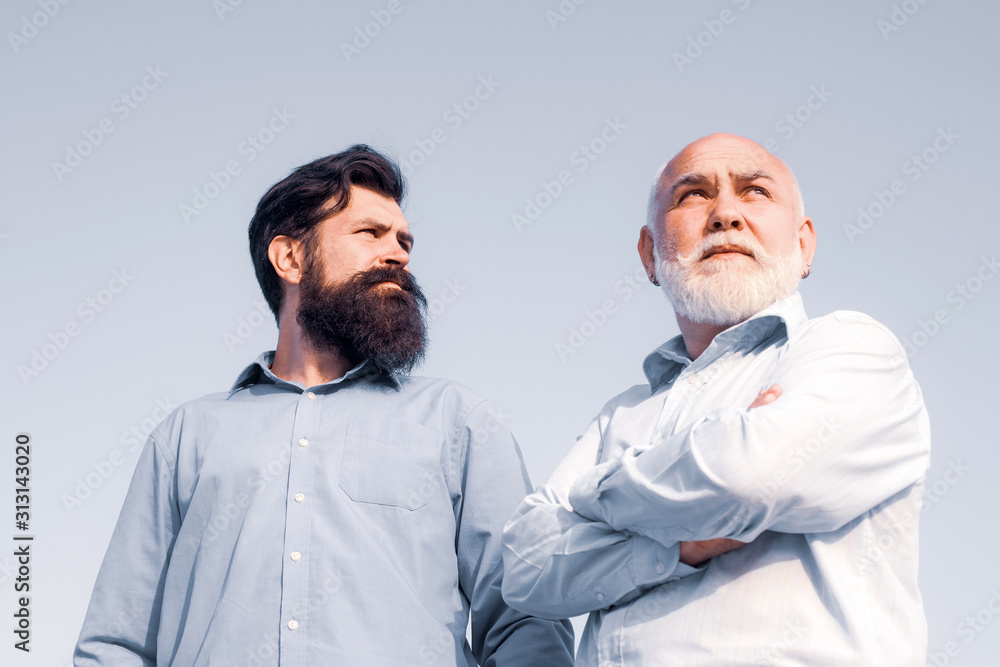 Two men: grandfather and father together. Fatherhood. Grandfather with son in park. Handsome senior men in blue shirt. Father and son relaxing together. Two men: grandfather and father together. Fatherhood. Grandfather with son in park. Handsome senior men in blue shirt. Father and son relaxing together.
