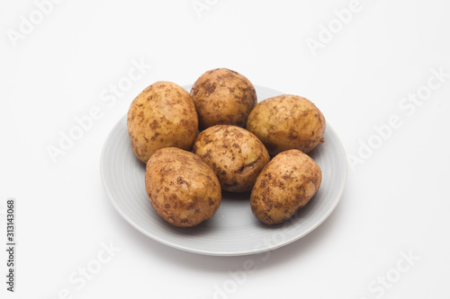 Raw potatoes in plate isolated