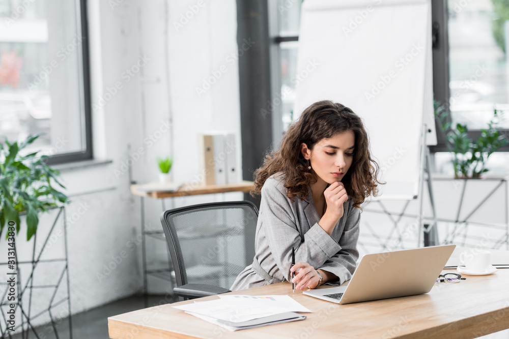 pensive account manager sitting at table and looking at laptop pensive account manager sitting at table and looking at laptop