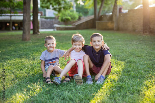 Tablou pe pânză Three happy young boys in summer park