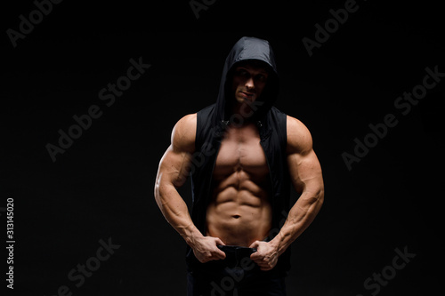 Muscular bodybuilder with jar of protein on a dark background. Sports nutrition. Bodybuilding nutrition supplements, sport, workout, healthy lifestyle concept.