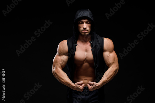 Muscular bodybuilder with jar of protein on a dark background. Sports nutrition. Bodybuilding nutrition supplements, sport, workout, healthy lifestyle concept.